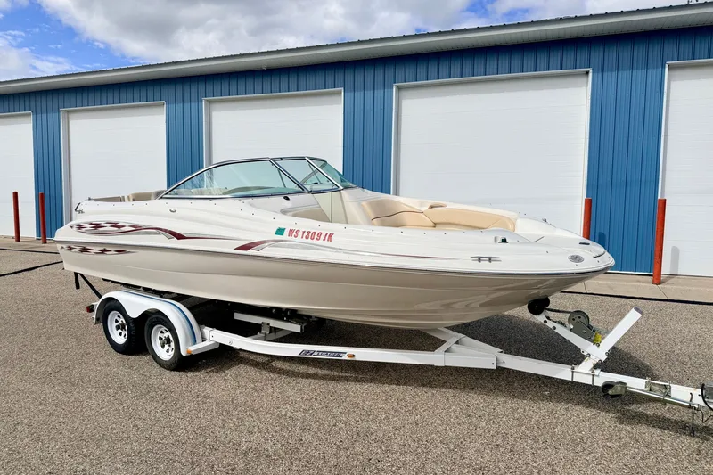 Slide: The Image of 2000 Sea Ray 210 Sundeck boat on trailer, parked near blue storage units. - 4