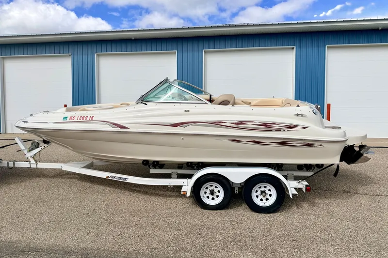 Slide: The Image of 2000 Sea Ray 210 Sundeck boat on trailer, parked outside blue garage. - 3