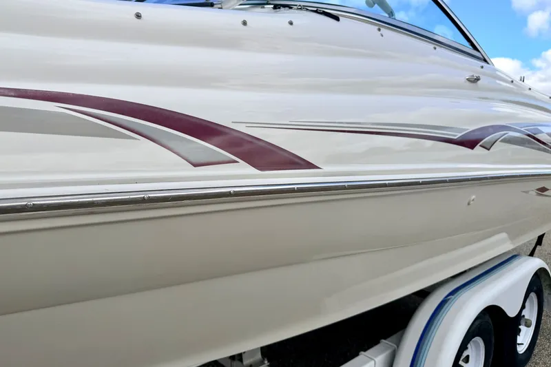 Slide: The Image of 2000 Sea Ray 210 Sundeck boat with sleek maroon and gray graphics on the side. - 8