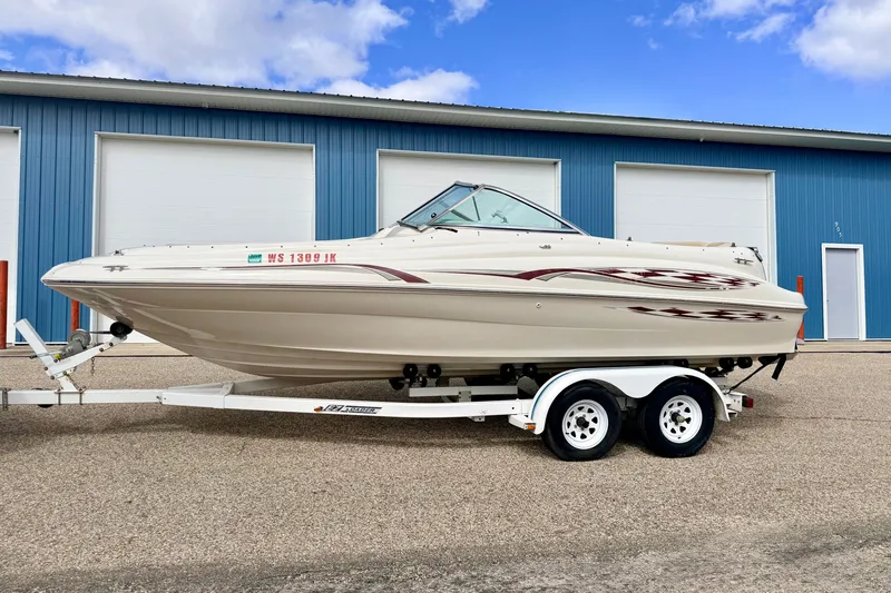 Slide: The Image of 2000 Sea Ray 210 Sundeck boat on trailer, parked outside blue building. - 5
