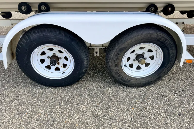 Slide: The Image of Trailer wheels for 2000 Sea Ray 210 Sundeck on asphalt surface. - 75