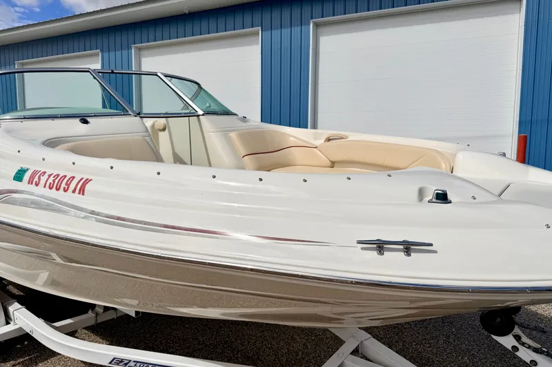 Slide: The Image of 2000 Sea Ray 210 Sundeck boat on trailer, parked near blue building. - 10