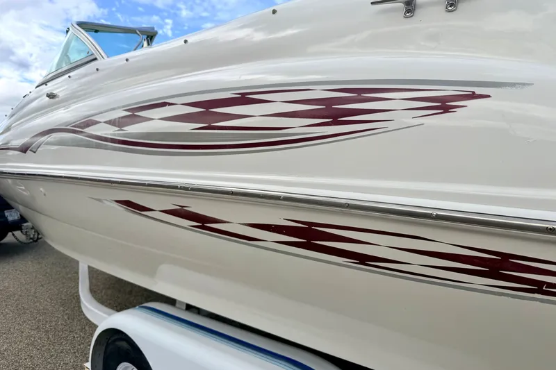 Slide: The Image of 2000 Sea Ray 210 Sundeck boat with red geometric graphics on white hull. - 9