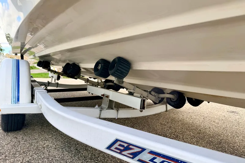 Slide: The Image of 2000 Sea Ray 210 Sundeck on trailer, showcasing hull and rollers. - 76