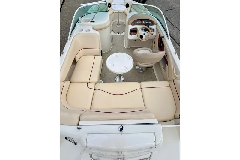 Slide: The Image of 2000 Sea Ray 210 Sundeck interior with beige seating and steering console. - 57
