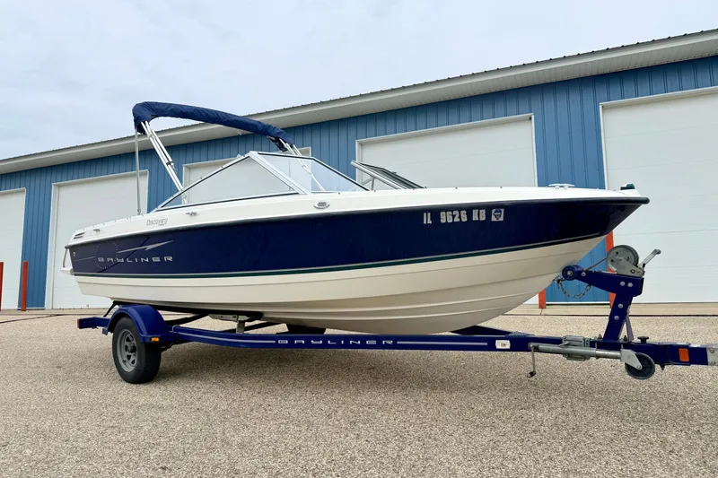 Slide: The Image of 2007 Bayliner 195 Discovery boat on trailer, parked outside blue building. - 0