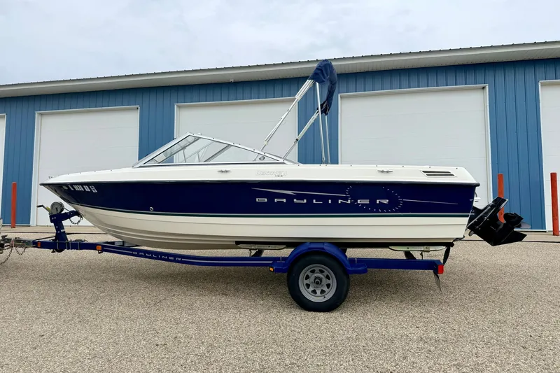 Slide: The Image of 2007 Bayliner 195 Discovery boat on trailer, parked near blue storage units. - 5