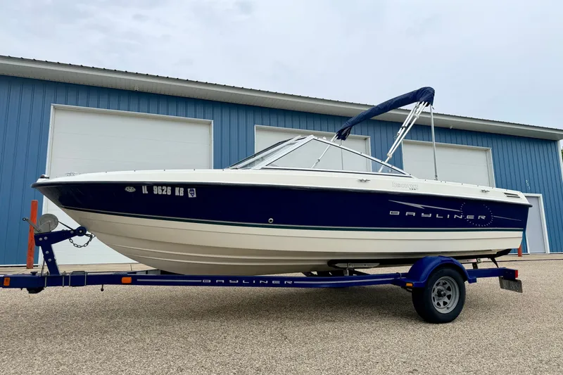 Slide: The Image of 2007 Bayliner 195 Discovery boat on trailer, parked outside blue warehouse. - 1