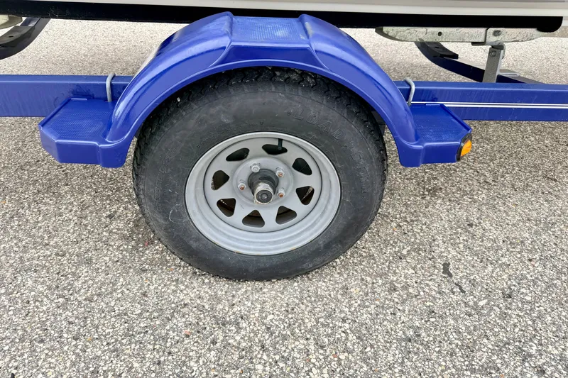Slide: The Image of Blue trailer wheel of 2007 Bayliner 195 Discovery on asphalt surface. - 57