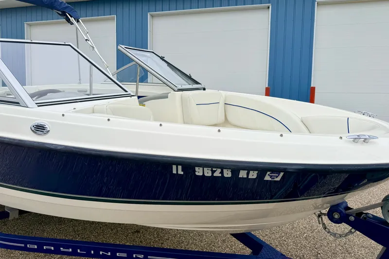Slide: The Image of 2007 Bayliner 195 Discovery boat on trailer, parked near blue building. - 11