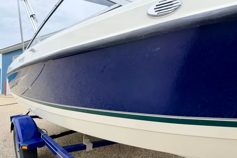 Slide: The Image of 2007 Bayliner 195 Discovery boat on trailer, featuring sleek blue and white design. - 13