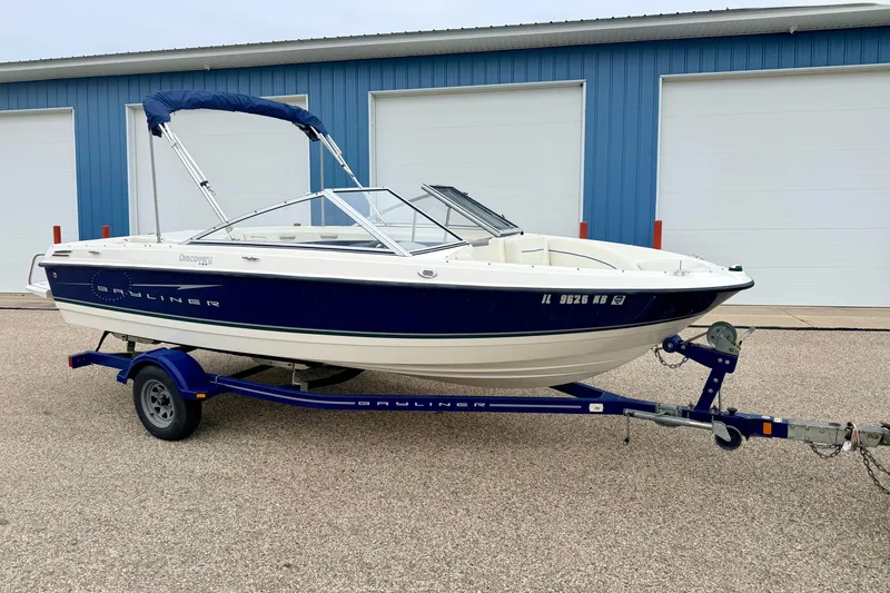Slide: The Image of 2007 Bayliner 195 Discovery boat on trailer, parked outside blue building. - 2