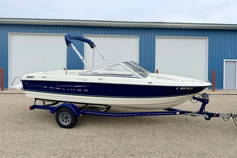 Slide: The Image of 2007 Bayliner 195 Discovery boat on trailer, parked outside blue building. - 4