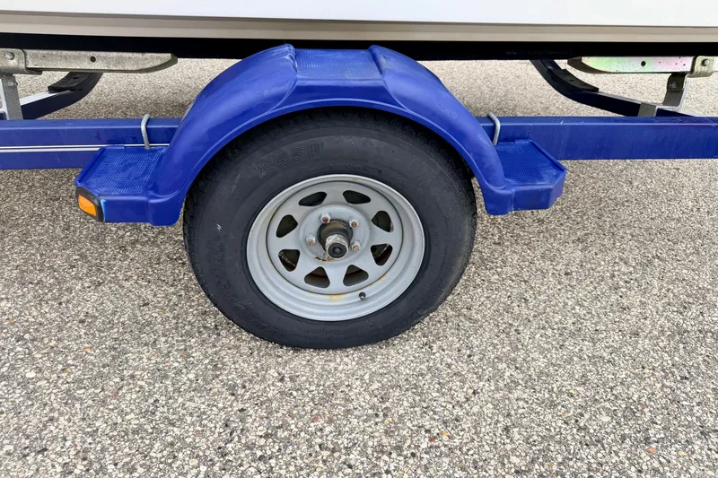 Slide: The Image of Trailer wheel of a 2007 Bayliner 195 Discovery boat on asphalt surface. - 56
