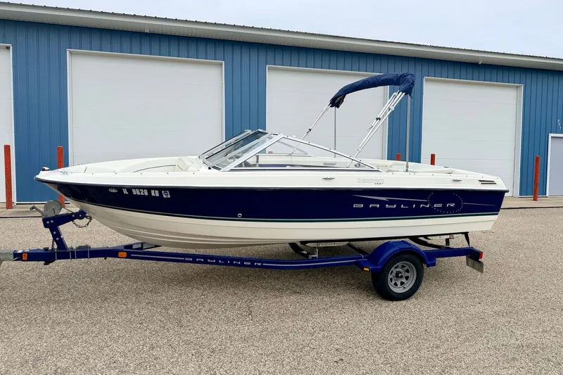 Slide: The Image of 2007 Bayliner 195 Discovery boat on trailer, parked outside blue warehouse. - 3