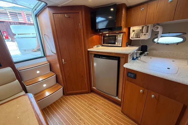 Slide: The Image of Interior of 2003 Tiara Yachts 3500 Open, featuring a compact kitchen with wood cabinetry. - 23