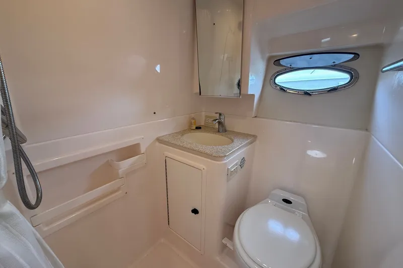 Slide: The Image of Bathroom interior of 2003 Tiara Yachts 3500 Open with sink, toilet, and porthole window. - 27