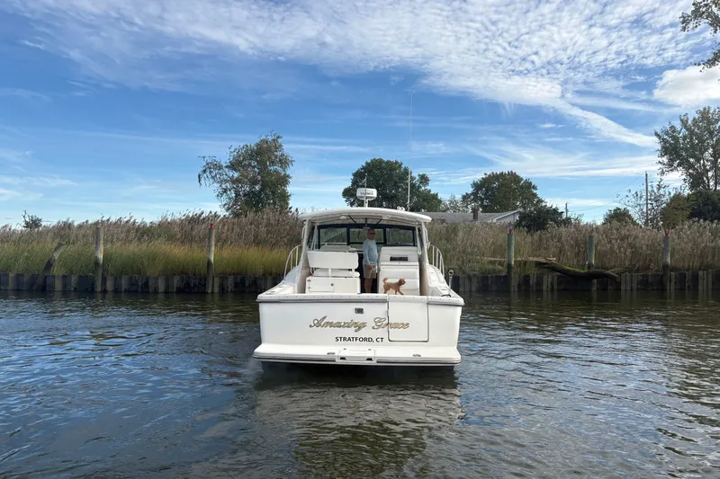 Slide: The Image of 2003 Tiara Yachts 3500 Open on water, rear view, with person and dog onboard. - 6
