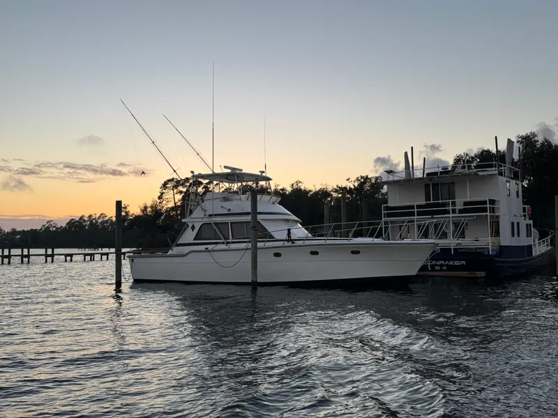 Slide: The Image of 1989 Ricker 48 Convertible yacht docked at sunset, calm waters, scenic background. - 3