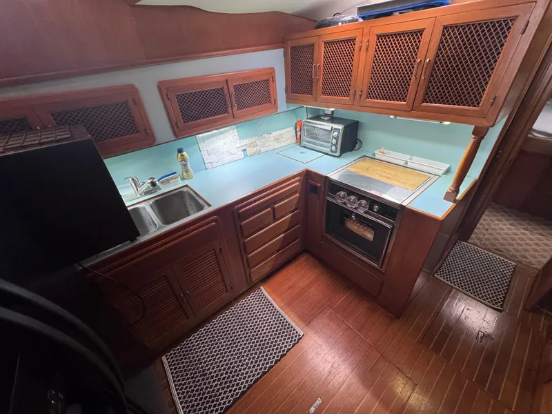 Slide: The Image of 1989 Ricker 48 Convertible yacht kitchen with wooden cabinets, blue countertops, and modern appliances. - 10