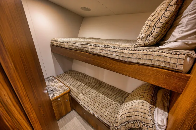 Slide: The Image of Cozy bunk beds in 1995 Merritt 65 Sport Fish yacht cabin, featuring wood accents and patterned bedding. - 51
