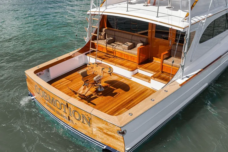 Slide: The Image of 1995 Merritt 65 Sport Fish yacht with wooden deck and seating, cruising on water. - 23