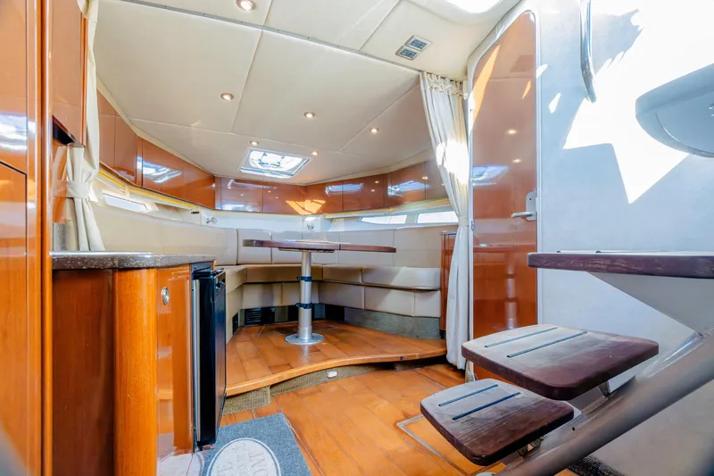 Slide: The Image of Interior of 2013 Sea Ray 370 Venture yacht, featuring elegant wood finishes and cozy seating area. - 36