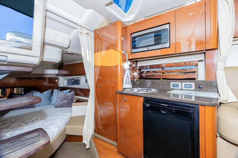 Slide: The Image of 2013 Sea Ray 370 Venture cabin interior with kitchenette, bed, and modern amenities. - 20