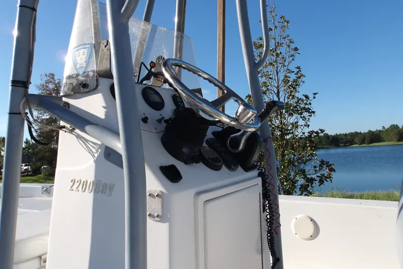 Slide: The Image of 2008 Ranger 2200 Bay boat console with steering wheel, near a serene lake. - 1