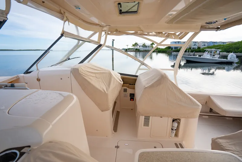 Slide: The Image of 2015 Grady-White Freedom 335 boat interior with covered seats, docked by calm waters. - 18