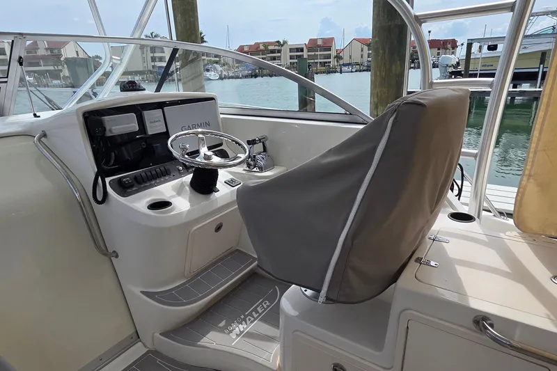 Slide: The Image of 2007 Boston Whaler 305 Conquest helm with Garmin navigation, docked by waterfront homes. - 34