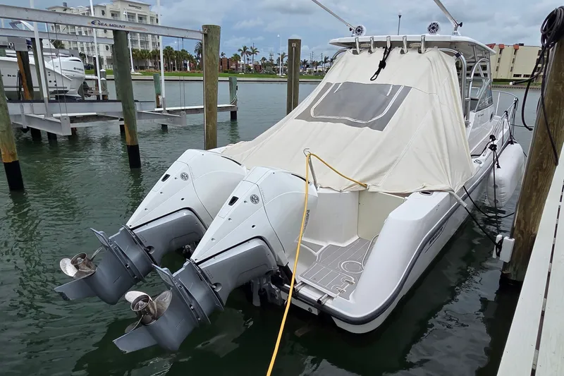 Slide: The Image of 2007 Boston Whaler 305 Conquest docked with covered cabin and twin outboard engines. - 57