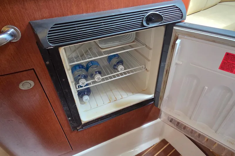 Slide: The Image of Mini fridge with water bottles inside a 2007 Boston Whaler 305 Conquest boat cabin. - 44