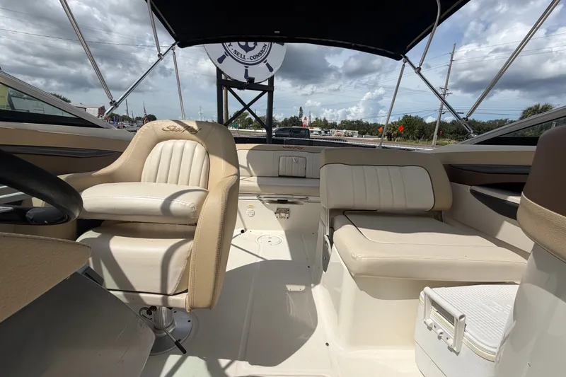 Slide: The Image of 2014 Sea Ray 240 Sundeck interior with beige seating under a canopy. - 67