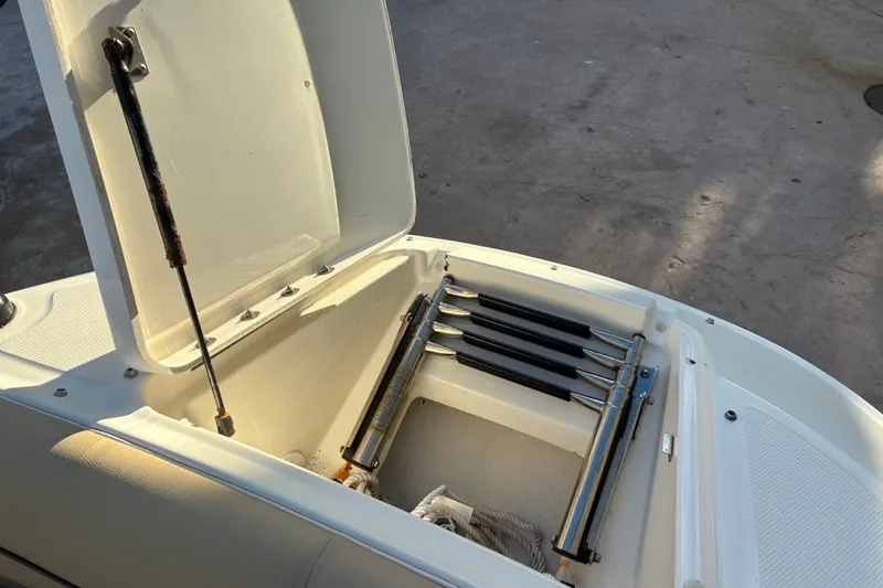Slide: The Image of Open storage compartment on a 2014 Sea Ray 240 Sundeck boat, showing a folded ladder. - 19