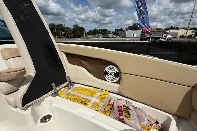 Slide: The Image of 2014 Sea Ray 240 Sundeck interior with storage compartment and speaker, under a cloudy sky. - 58