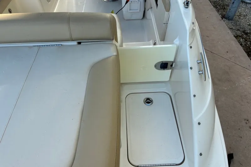 Slide: The Image of 2014 Sea Ray 240 Sundeck interior with beige seating and storage compartment. - 48