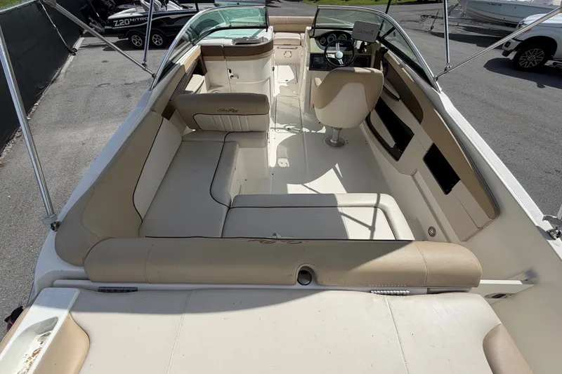 Slide: The Image of 2014 Sea Ray 240 Sundeck interior with beige seating and steering console. - 15