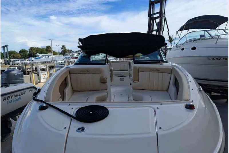 Slide: The Image of 2014 Searay SDX 240 boat with beige seating, docked at a marina under a blue sky. - 2