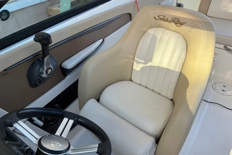 Slide: The Image of 2014 Sea Ray 240 Sundeck helm with beige captain's chair and steering wheel. - 31