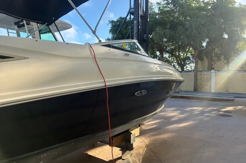 Slide: The Image of 2014 Sea Ray 240 Sundeck boat on a lift, surrounded by trees and sunlight. - 5