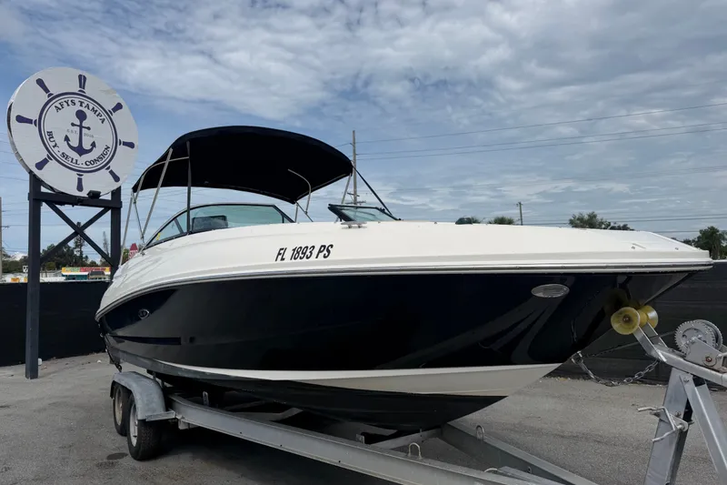 The Image of 2014 Sea Ray 240 Sundeck boat on trailer at dealership, under cloudy sky. - 0