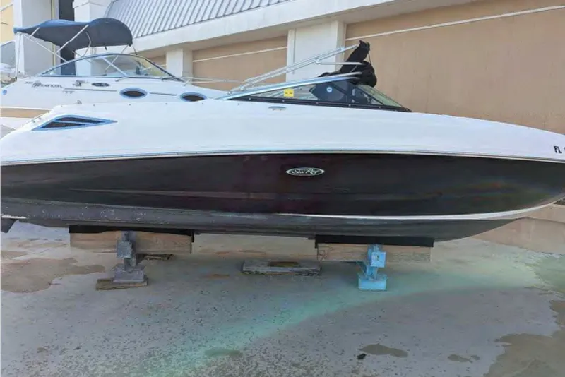 Slide: The Image of 2014 Searay SDX 240 boat on blocks, white and black hull, docked outdoors. - 1