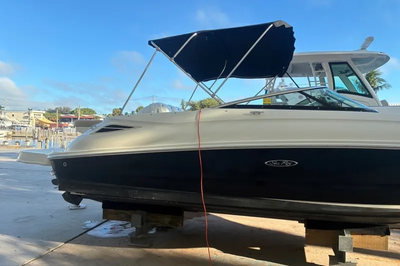 Slide: The Image of 2014 Sea Ray 240 Sundeck boat with blue canopy, docked on a sunny day. - 4