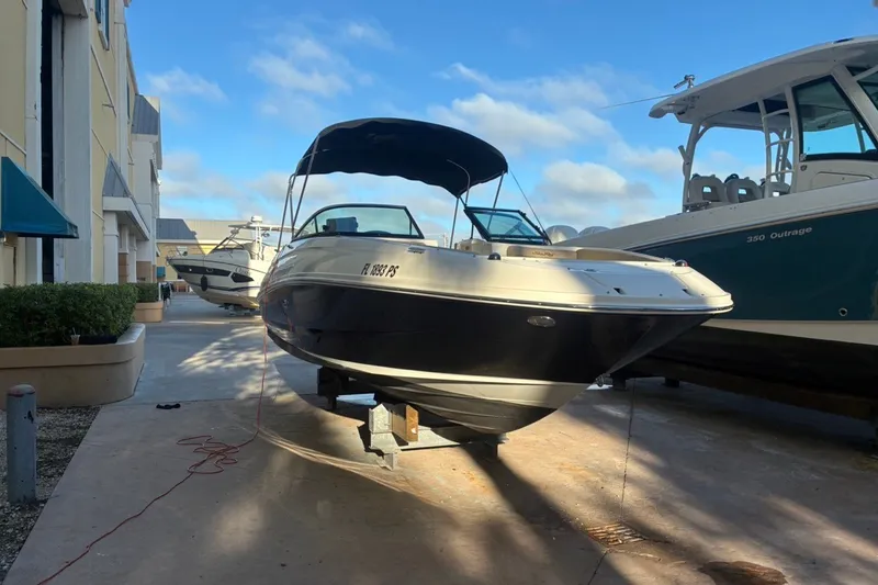 Slide: The Image of 2014 Sea Ray 240 Sundeck boat docked outdoors under a clear blue sky. - 1