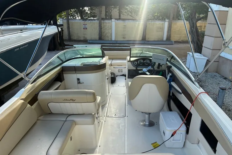 Slide: The Image of 2014 Sea Ray 240 Sundeck interior with seating and steering wheel under canopy. - 26