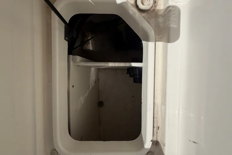 Slide: The Image of An open storage compartment on a boat with white walls and a black cable. - 18