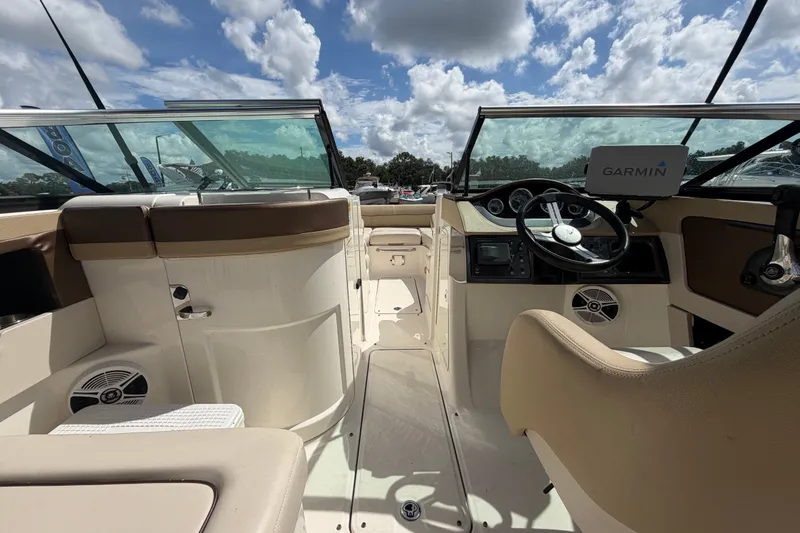 Slide: The Image of 2014 Sea Ray 240 Sundeck interior with Garmin navigation, beige seating, and clear skies. - 23