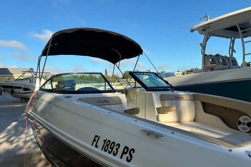 Slide: The Image of 2014 Sea Ray 240 Sundeck boat with canopy, docked under clear blue sky. - 14