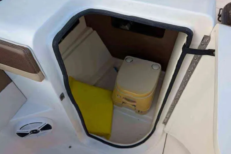 Slide: The Image of Interior of 2014 Searay SDX 240 boat with portable toilet and yellow cushion. - 7